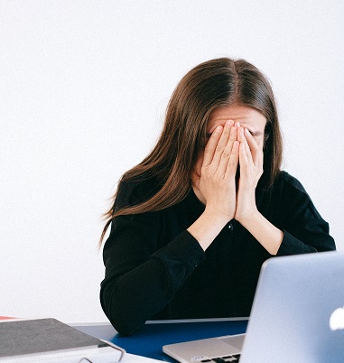 A woman is crying at her desk in front of the laptop