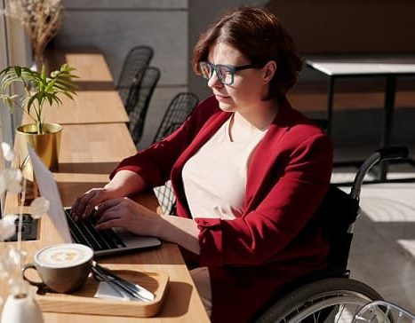 Women in a wheelchair is working on her laptop
