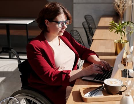 a women in a wheelchair is working on her laptop