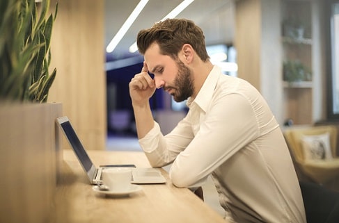 Man in white shirt looking at laptop