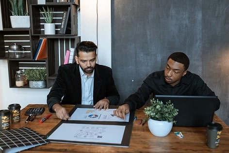 Men seated in office looking at charts