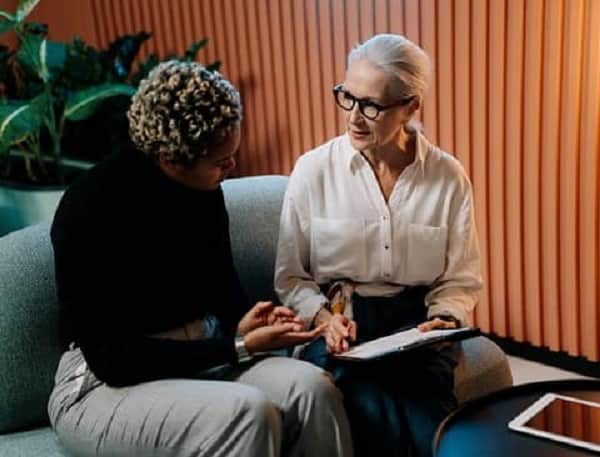 Women sitted on gray couch having a one-on-one meeting