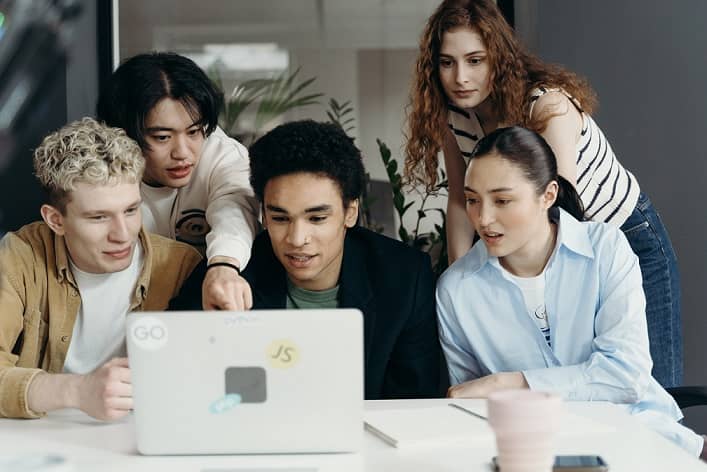 diverse people looking at a laptop