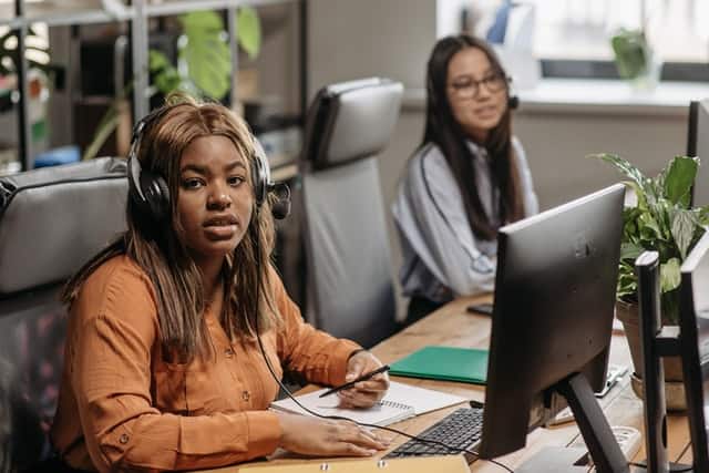 customer service representative sitting down in office behind her laptop wearing headset 