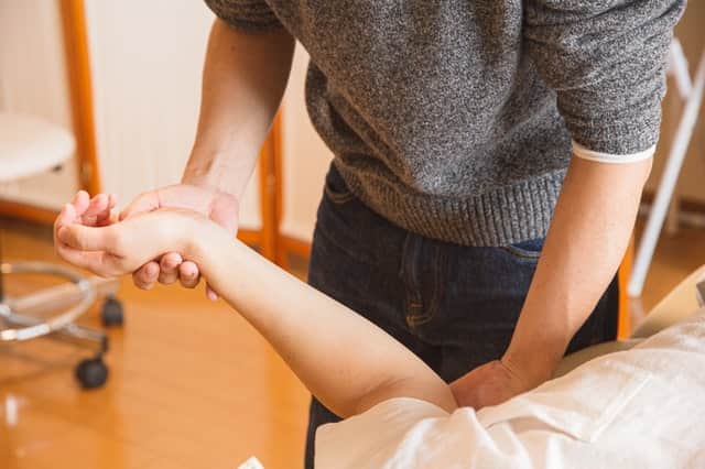 occupational therapist doing therapy on patient's left hand