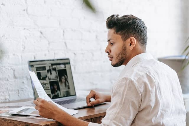 A man sitted on a desk works on his laptop