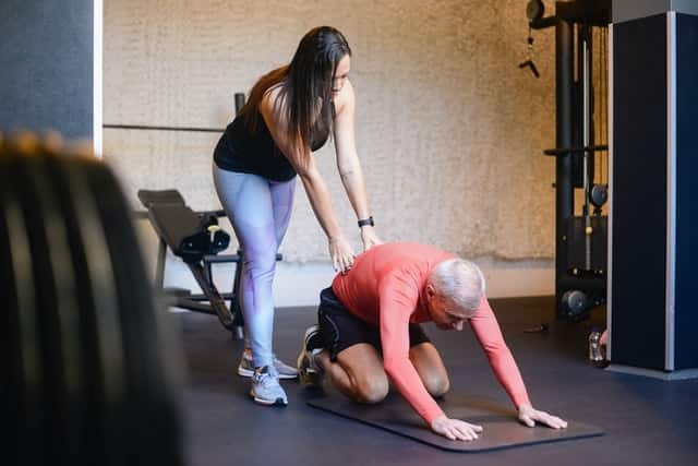 female personal trainer helping senior citizen man