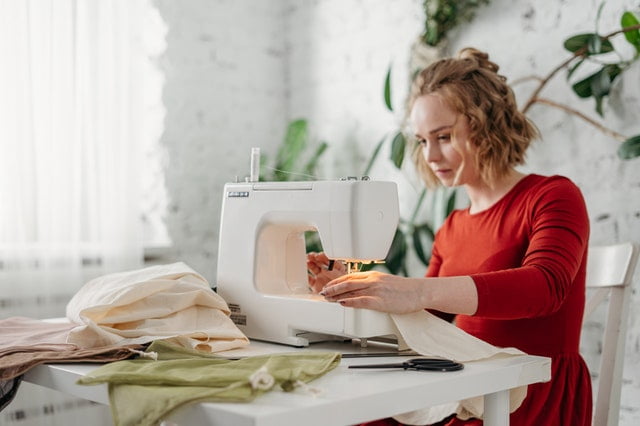 A woman working with her sewing machine and plants behind her