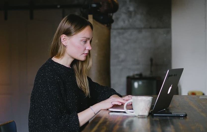 a-woman-is-sitting-on-a-table-working-on-her-computer