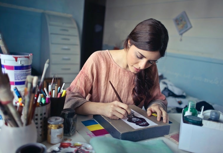Woman sitting on her working desk is painting